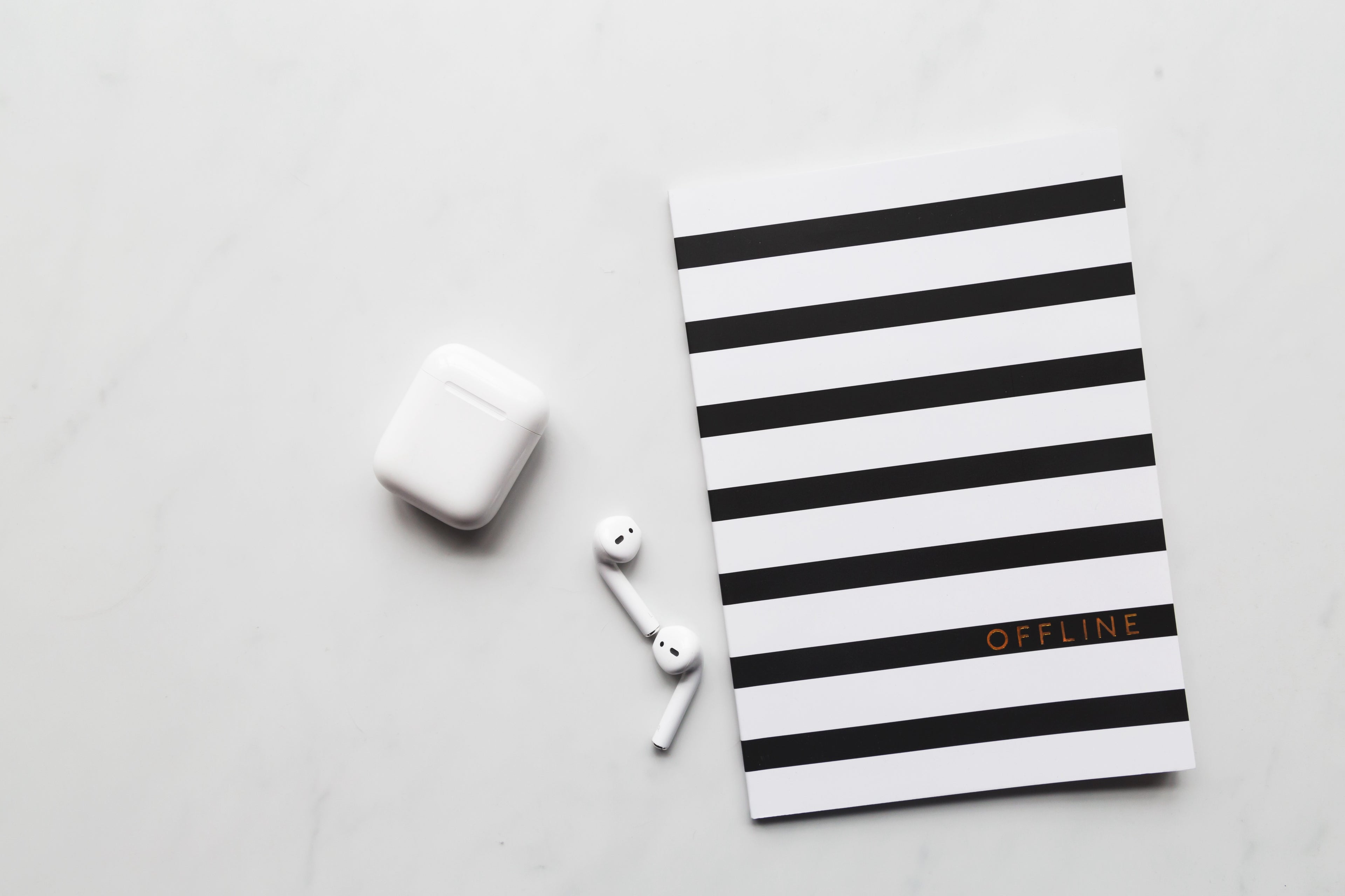 electronics gadgets - AirPods and notebook on desk